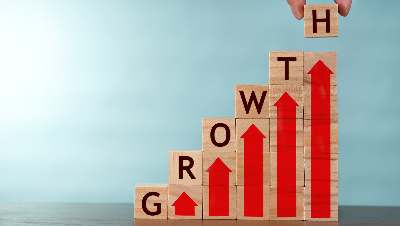 Stacked wooden blocks spelling GROWTH with red arrows, symbolizing business success and upward momentum for A&C Enterprises.